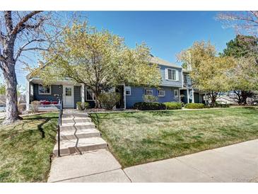 Charming townhome with beautiful landscaping and a welcoming front porch and entryway on a sunny day at 1907 S Balsam St, Lakewood, CO 80227