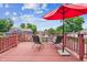 Outdoor deck with metal table and chairs and bright red umbrella for shade at 693 Delwood Ct, Highlands Ranch, CO 80126