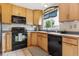 Well-lit kitchen equipped with black appliances, light wood cabinetry, and a practical corner sink at 693 Delwood Ct, Highlands Ranch, CO 80126
