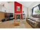 Comfortable living room features a fireplace with a red accent wall, large window, and cozy sofa at 693 Delwood Ct, Highlands Ranch, CO 80126