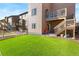 A well-maintained backyard featuring lush artificial grass, a patio, and a staircase leading to a balcony above at 1914 Villageview Ln, Castle Rock, CO 80104