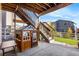 A covered patio beneath a second-story deck, with a wooden playhouse and string lights creating an inviting outdoor space at 1914 Villageview Ln, Castle Rock, CO 80104