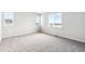Large bedroom featuring two windows, neutral carpet, white walls, base trim and several electrical outlets at 5742 Ranch St, Mead, CO 80504