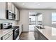 Bright kitchen showcasing stainless steel appliances, light gray cabinets, island sink, and a sliding glass door to the backyard at 5742 Ranch St, Mead, CO 80504