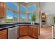 Sunlit kitchen features a stainless steel dishwasher, wood cabinets, and views of an inviting brick fireplace at 10534 Inspiration Dr, Parker, CO 80138