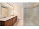 Bathroom featuring double sink vanity, tile floors, and a glass enclosed shower at 11978 W Aqueduct Dr, Littleton, CO 80127