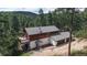 Stunning aerial view of a rustic home with an attached garage and lush forest backdrop on a sunny day at 2545 N State Highway 67, Sedalia, CO 80135