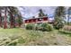 Spacious green backyard showcasing a two-story house with a deck and surrounding trees at 2545 N State Highway 67, Sedalia, CO 80135