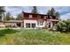 Large grassy backyard featuring a two-story house with wood and stucco, and an outdoor patio at 2545 N State Highway 67, Sedalia, CO 80135