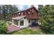 Rustic home exterior with a large deck, multiple windows, and a lush yard surrounded by mature trees at 2545 N State Highway 67, Sedalia, CO 80135