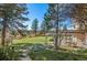 Lush backyard with mature trees, stone patio, and manicured lawn offering a serene outdoor space at 8544 Burning Tree Trl, Franktown, CO 80116