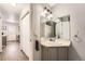 Bathroom features a vanity, mirror, and grey cabinets, with a partial view of the kitchen at 8391 W 90Th Pl # 101, Westminster, CO 80021