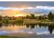 Tranquil water view at sunset featuring beautiful homes, trees, and reflections in the calm water at 3216 Country Club Pkwy, Castle Rock, CO 80108