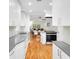 Open kitchen with white cabinetry, stainless steel appliances, and hardwood floors at 3739 W 46Th Ave, Denver, CO 80211