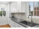 Bright kitchen with stainless steel sink, white cabinets, light countertops, and herringbone tile backsplash at 3739 W 46Th Ave, Denver, CO 80211