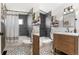 Updated bathroom features black and white patterned tile, tub with shower, and modern vanity at 10810 W Alamo Pl, Littleton, CO 80127