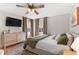 Cozy main bedroom features a ceiling fan, mounted TV, large windows, and neutral decor at 10810 W Alamo Pl, Littleton, CO 80127