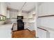 Kitchen with white cabinets, black appliances, and wood floors at 1530 S Quebec Way # 24, Denver, CO 80231