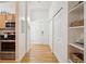 Bright hallway with hardwood floors, white walls, closet doors, and view of the kitchen area at 444 17Th St # 208, Denver, CO 80202