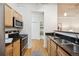 Kitchen featuring wood cabinets, black countertops, stainless steel appliances, and view into hallway at 444 17Th St # 208, Denver, CO 80202