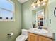 Cozy bathroom features a toilet, sink with vanity, window, and light green paint at 9770 Dahlia Ln, Thornton, CO 80229