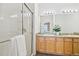 Bright bathroom featuring double sinks, wood cabinets, tile floors, and a glass door shower at 9770 Dahlia Ln, Thornton, CO 80229