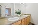 Clean bathroom with a double vanity, wood cabinets, light fixtures, and view into the bedroom at 9770 Dahlia Ln, Thornton, CO 80229
