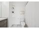 Clean bathroom with a toilet, gray vanity, shelves, shower, and gray floors at 9770 Dahlia Ln, Thornton, CO 80229
