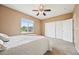 Neutral bedroom featuring plush carpet, ceiling fan, view of the outside, and double door closet at 9770 Dahlia Ln, Thornton, CO 80229