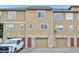 Townhome featuring a stone facade, garage, wood siding, and red front doors at 9770 Dahlia Ln, Thornton, CO 80229