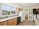 Bright kitchen with laminate flooring, light wood cabinets, a large window, and adjacent laundry room at 9770 Dahlia Ln, Thornton, CO 80229
