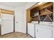 Bright laundry room with a white washer and dryer, shelves, storage cabinet, and vinyl floors at 9770 Dahlia Ln, Thornton, CO 80229