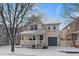 Two-story house with a front porch, gray garage door, and snowy yard at 9442 E 106Th Dr, Commerce City, CO 80640