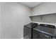 Modern laundry room features a new black washer and dryer, plus a shelf for storage at 4851 Cattle Cross Rd, Castle Rock, CO 80104