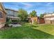 A beautiful grassy backyard featuring a gazebo, a fire pit, a brick outbuilding and mature trees at 521 Harrison St, Denver, CO 80206