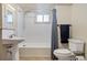 Bright bathroom with a pedestal sink, white tiled shower/tub, and modern fixtures at 521 Harrison St, Denver, CO 80206