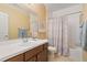 Bright bathroom with a white tiled countertop, wood cabinets and shower with patterned curtain at 10182 Bristleridge St, Parker, CO 80134