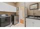 Well-equipped laundry room features modern washer/dryer, a sink with chrome faucet, and ample white cabinetry at 10182 Bristleridge St, Parker, CO 80134