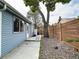 Side yard featuring a charming wooden fence, a mature shade tree, and low-maintenance rock landscaping at 10025 W 8Th Ave, Lakewood, CO 80215