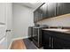 Well-equipped laundry room with modern washer and dryer, dark cabinetry, and a sink at 7606 S Valleyhead Ct, Aurora, CO 80016