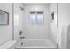 Modern bathroom features white tiles, a shower-tub combo, and a window, creating a clean and functional space at 9230 Aspen Dr, Thornton, CO 80229