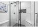 Modern shower enclosed in glass, showcasing sleek fixtures, marble-like tile, and a built-in shower caddy at 9230 Aspen Dr, Thornton, CO 80229