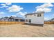 Spacious, unfinished backyard enclosed by a wooden fence with a two-story white house and blue sky at 6207 E 155Th Pl, Brighton, CO 80602