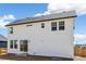 Back exterior view of a white two-story home with sliding glass doors leading to a patio and dark roof at 6207 E 155Th Pl, Brighton, CO 80602