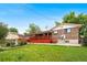 Exterior view of backyard featuring a large red deck and green grass and greenery at 6336 W 71St Pl, Arvada, CO 80003