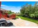 Exterior view of backyard featuring a large red deck with hot tub and green grass and greenery at 6336 W 71St Pl, Arvada, CO 80003