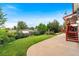Exterior view of backyard featuring a large red deck and green grass and greenery at 6336 W 71St Pl, Arvada, CO 80003