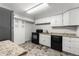 Galley kitchen features white cabinets, black appliances, granite counters and gray faux tile flooring at 6336 W 71St Pl, Arvada, CO 80003