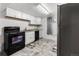 Galley kitchen features white cabinets, black appliances, granite counters and gray faux tile flooring at 6336 W 71St Pl, Arvada, CO 80003