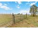A wire fence leads to the property, surrounded by a green field and beautiful sky at 1604 Lisbon Dr, Parker, CO 80138